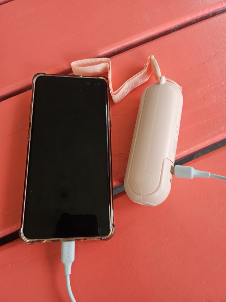 JISULIFE 3-in-1 handheld fan charging a phone with power bank function