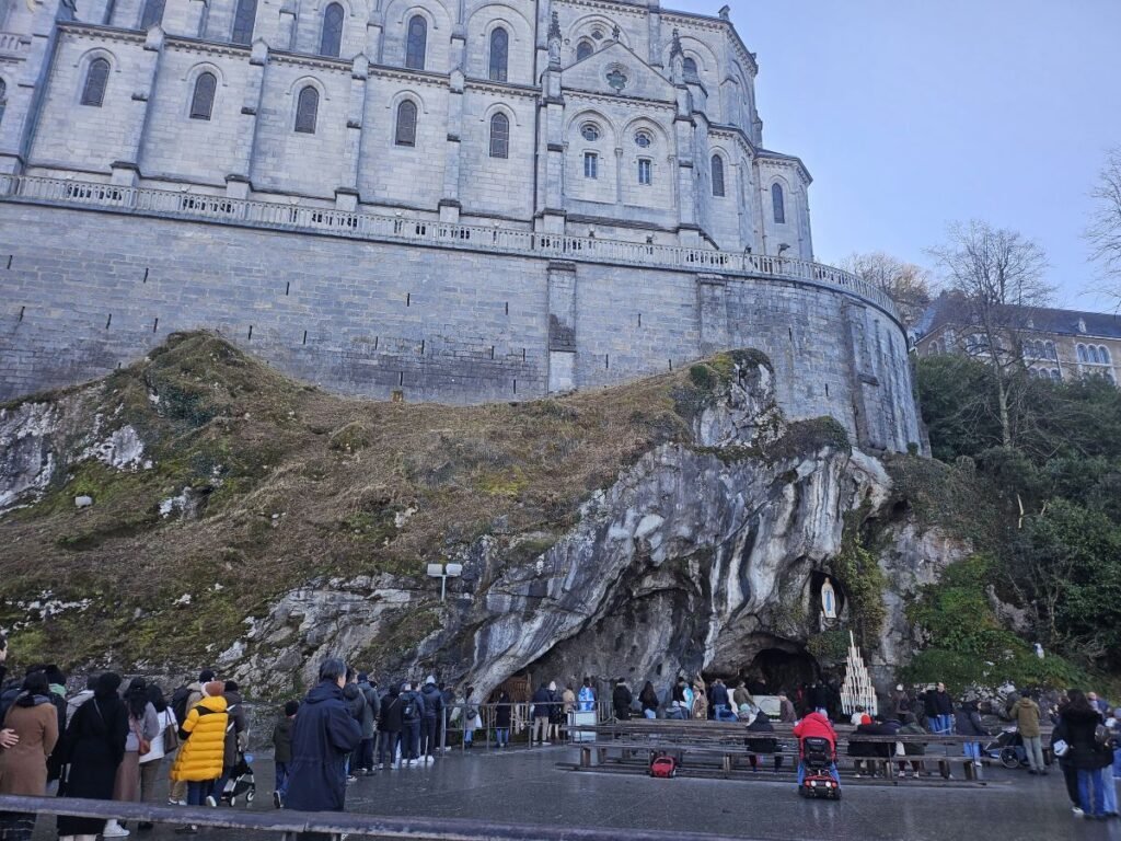 Pilgrims praying at the Grotto of Massabielle in Lourdes