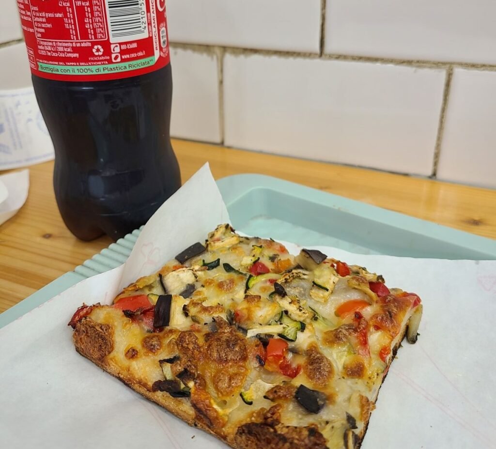 Slice of Roman pizza with a Coca-Cola